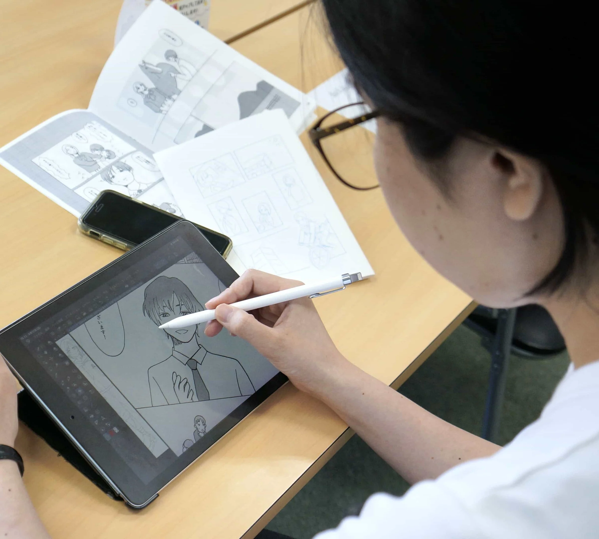 原稿用紙にペンでマンガを描く受講生