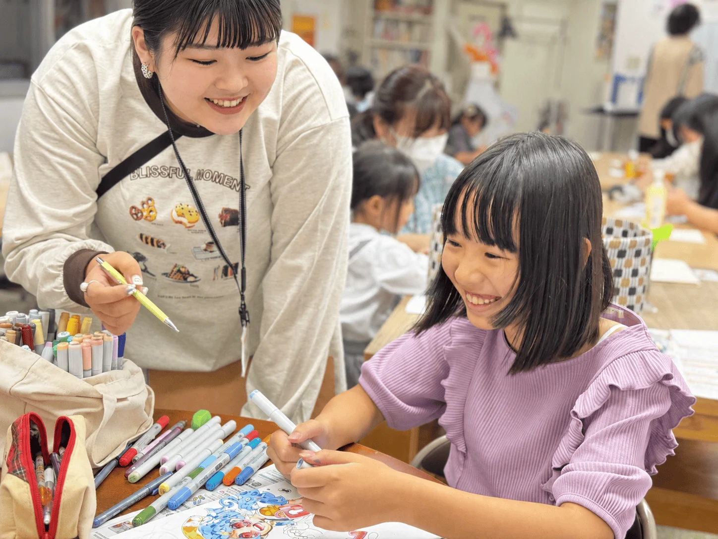 講師と生徒が笑顔で画材を選ぶ様子