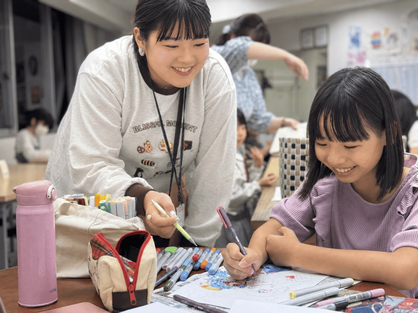 講師に見守られながらイラストを彩色する生徒