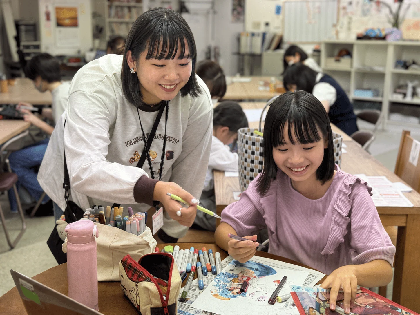 作品を見ながら講師のアドバイスを聞く生徒