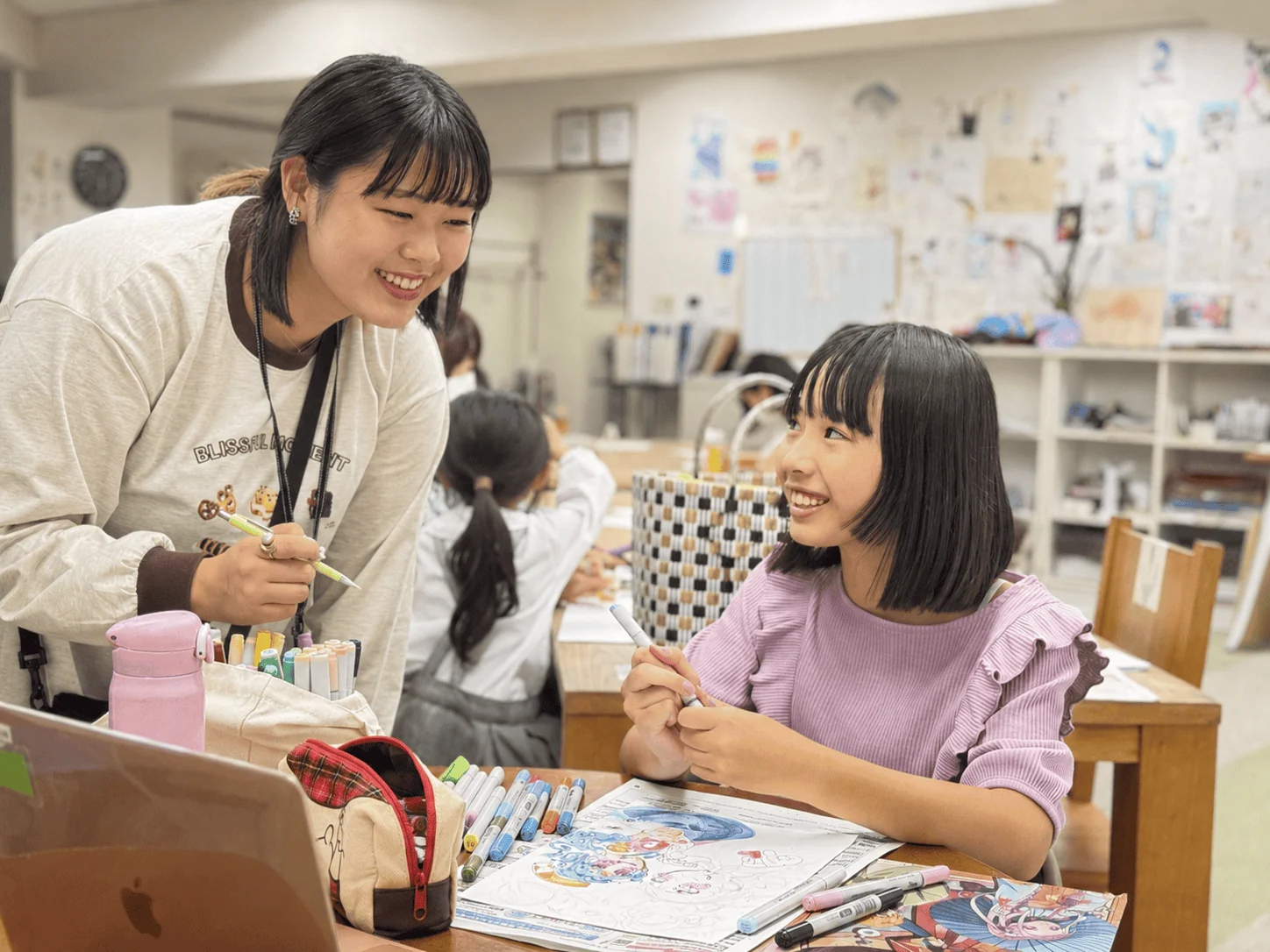 描きかけの作品について笑顔で話す講師と生徒