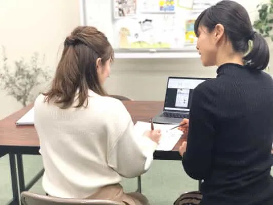 教室のテーブルでスタッフに相談する来校者