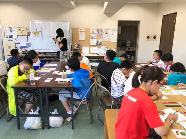 海外から来校した子どもたちが講師の説明を聞きながらマンガ体験に参加する教室