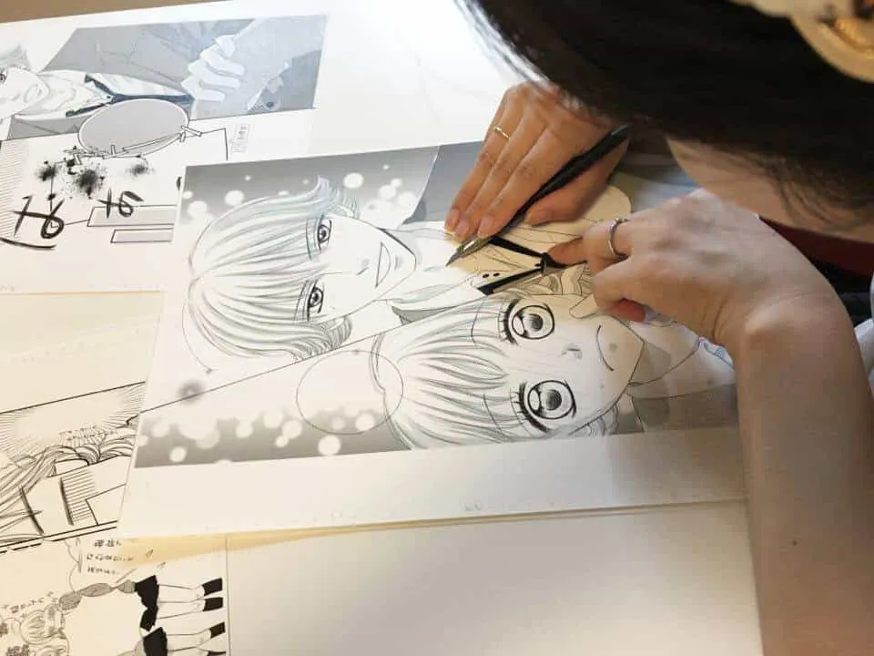 原稿用紙にペンでマンガを描く受講生