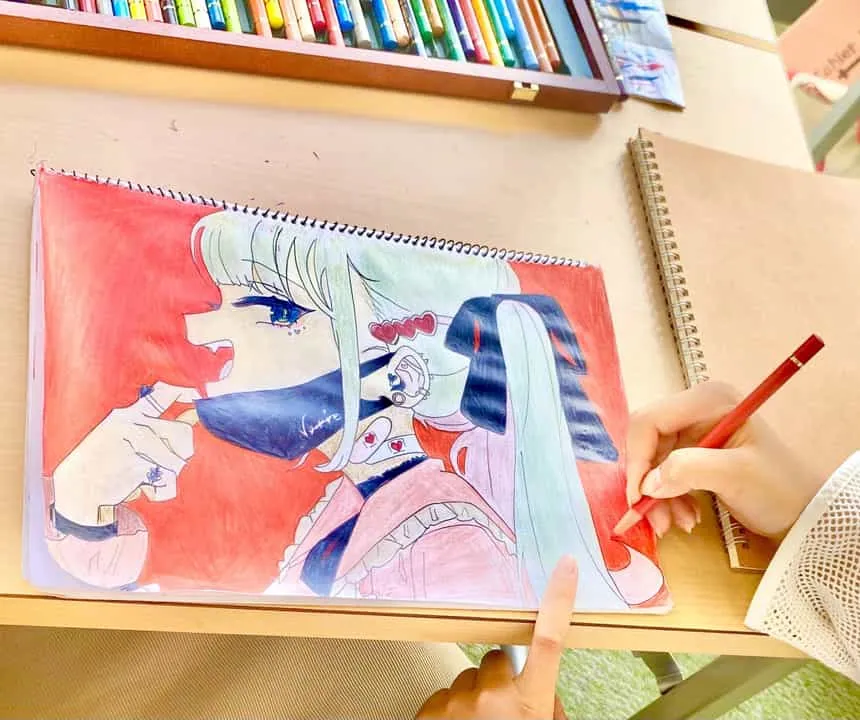 色鉛筆でキャラクター作品を仕上げる子どもの手元